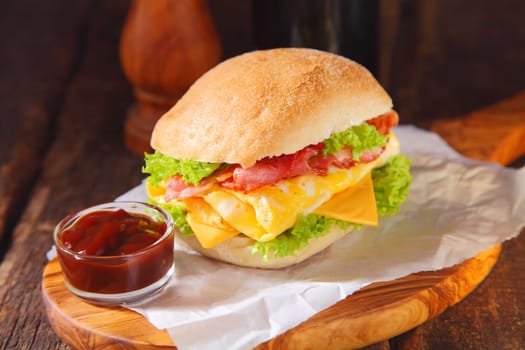 Close up Healthy Egg Burger with Ketchup on Saucer Placed on Burger Paper Above Wooden Serving Board.