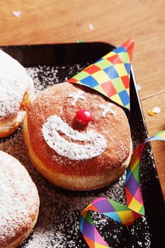 Close up Delicious Sugared Donuts on Tray with Clown Face and Carnival Props on Top of Wooden Table.