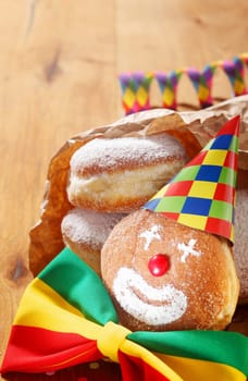 Close up Carnival Donuts with Clown Face Decorated with Colored Hat and Ribbon on Wooden Table.