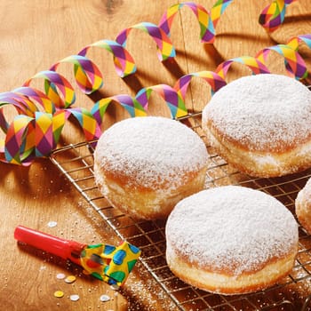 Close up Delicious Powdered Sugar Raised Donuts on Screen with Carnival Props on Top of Wooden Table
