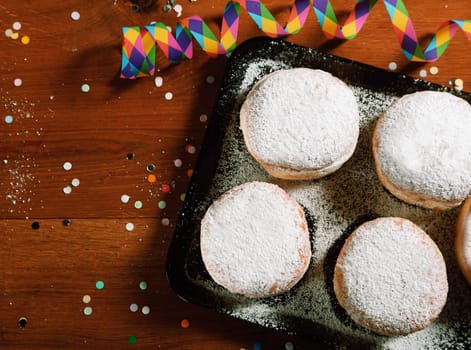 Close up Carnival Donuts on Black Tray with Powdered Sugar, Placed on Wooden Table with Props on Sides.