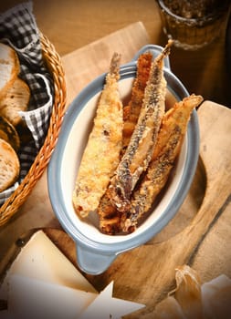 Close up Appetizing Batter Fried Fish on Bowl. Placed on Wooden Table with Bread and Cheese.