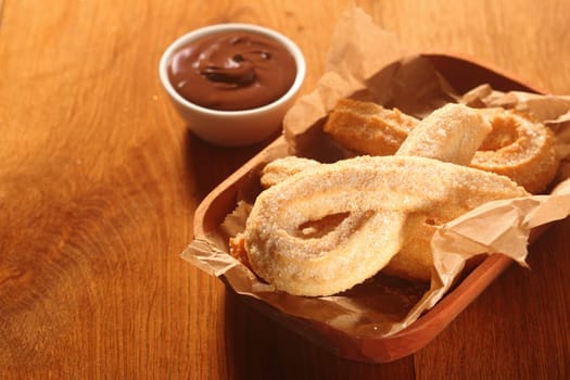 Close up Tasty Churro Recipe with Chocolate Dip Sauce on Side, Placed on Wooden Table.