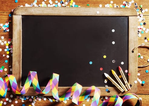 Close up Carnival Black Board, Decorated with Confetti, with Copy Space on Wooden Background.