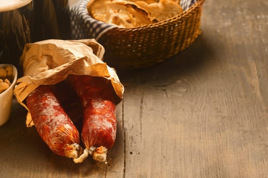 Spicy dried Italian salami sausages in brown paper wrapping on a rustic wooden kitchen counter with copyspace