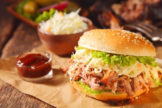 Gourmet Pulled Pork Burger with Ketchup Sauce on Paper Above Wooden Table.