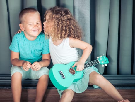 Portrait of a cute kids sitting ouddoor with ukulele