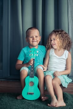 Portrait of a cute kids sitting ouddoor with ukulele