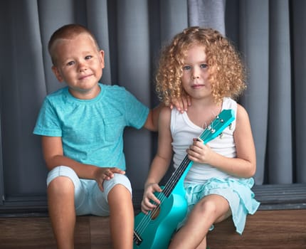 Portrait of a cute kids sitting ouddoor with ukulele