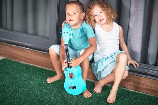 Portrait of a cute kids sitting ouddoor with ukulele