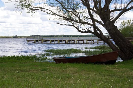 boats and dock on river very grown sky with clouds
