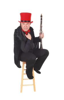 A middle age indigenous man playing his clarinet in a black outfit and.red hat and bow, isolated for white background.