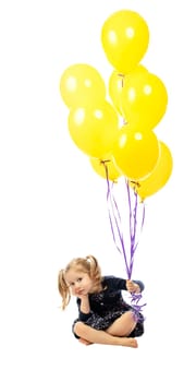 bored little girl sitting on the floor holding colorful balloons in hand. Isolated on white.