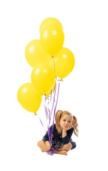 portrait of a 3 year old caucasian girl sitting and with colorful balloons. bored expression. isolated on white.