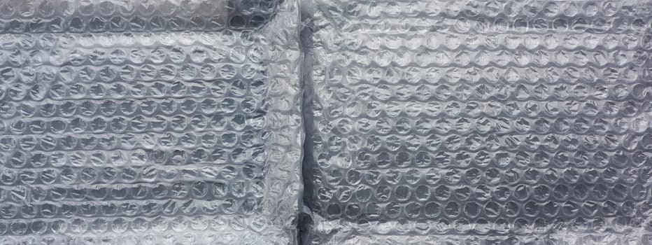 fragment of a transparent film with air for transportation of parcels is glued on gray polyethylene, inside of the envelope. White polyethylene texture.