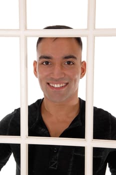 A happy east Indian man standing behind a white window frame in a.black dress shirt with a big smile, isolated for white background.
