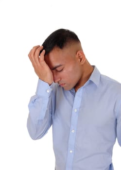 A handsome east Indian business man standing in the studio isolated.over white background, in a blue shirt with one hand on his forehead.thinking hard.