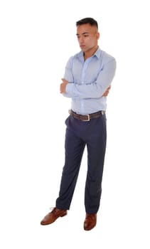 A handsome young east Indian man standing in a blue shirt with his.arms crossed, looking down, isolated for white background.
