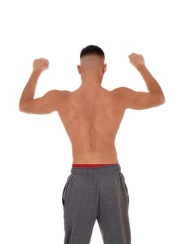 A handsome young east Indian man standing shirtless from the back.in track pants with red underwear, isolated for white background.