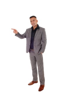 A handsome young man standing with his hands in his pocket in a gray.suit, pointing with one hand, isolated for white background.