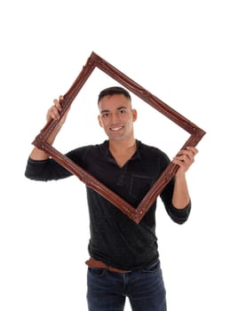 A happy east Indian man standing behind a brown picture frame in a.black dress shirt with a big smile, isolated for white background.