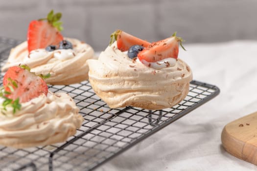 Small pavlova cakes with fresh raspberries and blueberries.