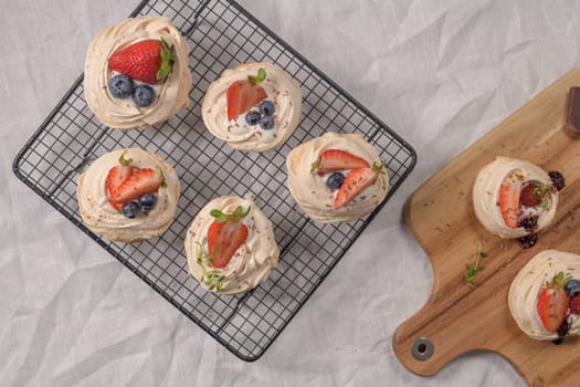 Small pavlova cakes with fresh raspberries and blueberries.