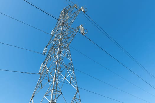 Electricity transmission pylon silhouetted against blue sky