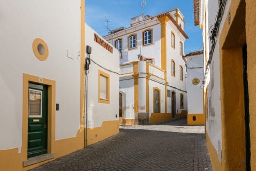 The view of narrow paved street of Evora with the cozy white houses. Evora. Alentejo. Portugal