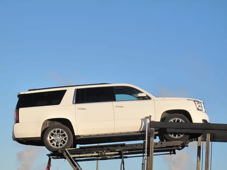Car is raised high up on a platform and flat bed and is being transported