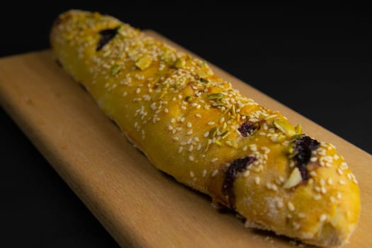 Freshly prepared puff pastry with cherry and sesame seeds close-up in a black background. Details The concept of home baking, breakfast, snack.