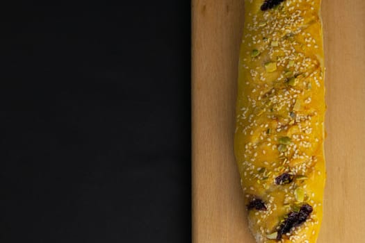 Freshly prepared puff pastry with cherry and sesame seeds close-up in a black background. Details The concept of home baking, breakfast, snack.