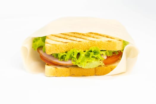 Sandwich of several slices of white bread on a wooden board. The filling of the sandwich consists of bacon, cheese and ham. Next cutlery and a cup of mustard. Dark wooden background. View from above.