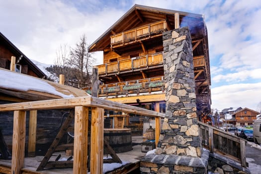 Les deux Alpes, Alps, France, January 2017 Tall stone chimney in front of traditional alpine wooden house. Popular ski and winter sport destination