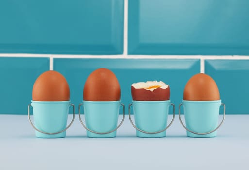Four boiled eggs in bucket eggcups in blue kitchen