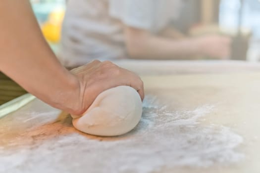 Person hand rolling out the dough made from flour, which will be used for the making of traditional chinese dumplings during cooking class in a travelers hostel, Chengdu, China