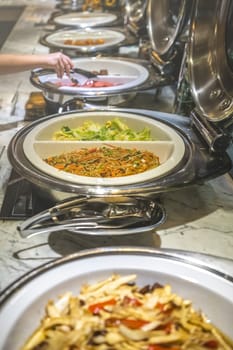 Fried noodles and boiled pakchoy in a serving bowl as a asian style breakfast buffet on the table in hotel cafeteria, China