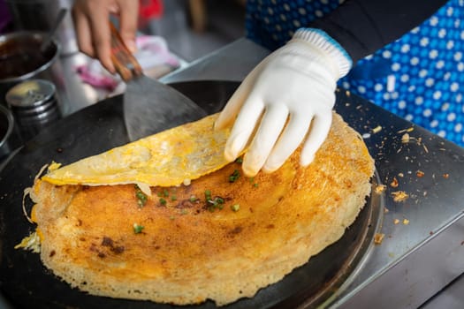 Woman folding and making savoury egg pancake in a small local street outlet bakery in Yichang town, China