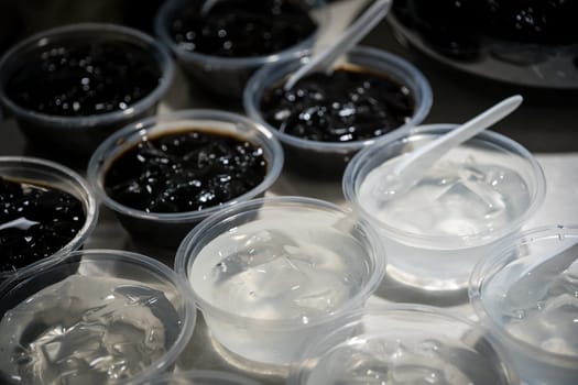 Plastic transparent bowls with sweet jelly chinese dessert on a self service breakfast buffet table in a restaurant