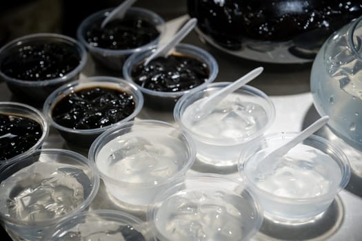 Plastic transparent bowls with sweet jelly chinese dessert on a self service breakfast buffet table in a restaurant