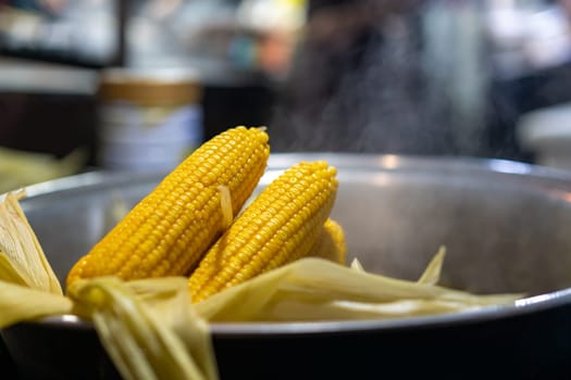 Freshly steamed corn in a metal bowl for sale on the street market in small town, China