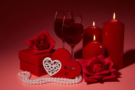 Gift boxes, two glasses with wine, burning candles, red roses and hearts on red background. Valentine's day. Wedding day.  Design element for romantic greeting card and invitation.