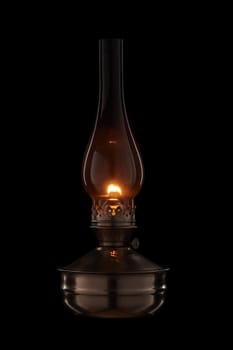 Vintage kerosene lamp burning on black background. Glass old oil lamp. Side view