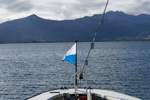 Impressions of the landscape, sky and clouds on Lake Chiemsee in Bavaria, with a flag on the bow of a Boat