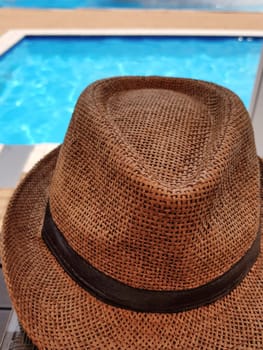 Close up of a summer hat and a blurry blue pool in the background..