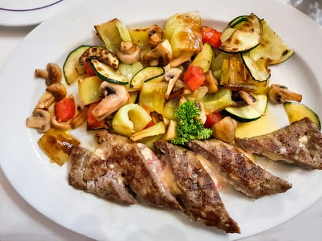 Main course. Pork stuffed with cheese. Attachment is a stewed vegetable. Mushrooms, tomatoes, peppers, zucchini.