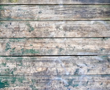 Old worn wood plank floor. Green, peeled colors. Engraved with various love and other inscriptions. Can be applied as background, template or texture.