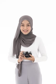 Portrait of happy young adult asian muslim female tourist and photographer holding a camera and smiling. Studio shot of woman isolated on white background