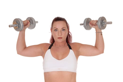 An exercising pretty woman standing in a sports bra and lifting.up the two dumbbells in her hand, isolated for white background.
