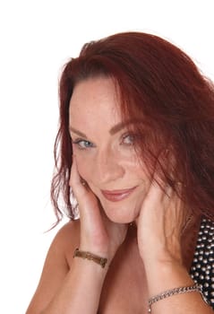 A close up image of the face of a pretty woman looking into the camera.with her blue eyes and her hand on her face.